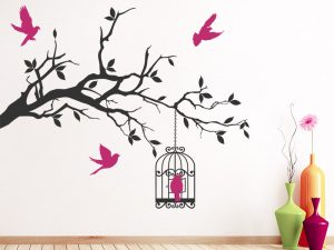 طرح برچسب دیواری یا استیکر روی دیوار که از گوشه دیوارشاخه بزرگ با قفس و پرندهای در حال پرواز نصب شده است