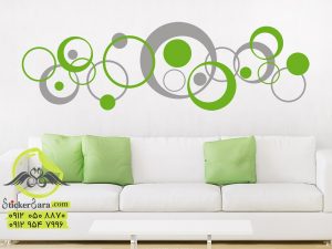استیکر دیواری تزینی دایره های مدرن در دو رنگ روی دیواردیواری تزینی دایره های مدرن در دو رنگ توسی و سبز روی دیوار پشت مبل